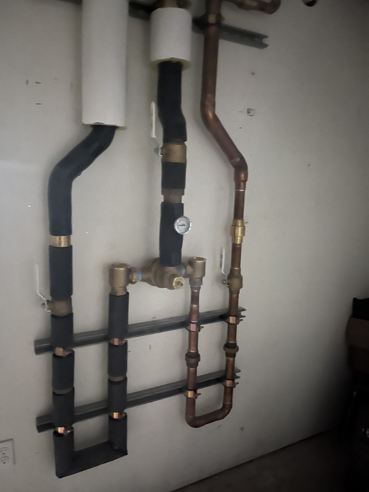 Copper water manifold with brass shutoff valves and a pressure gauge, installed by Lopez Plumbing