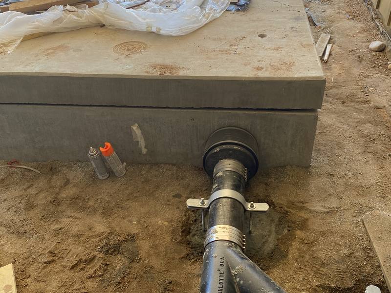 Underground drain line joined with a no-hub coupling beside a new concrete pad