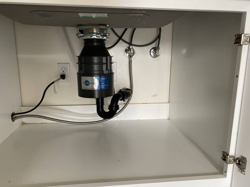 New garbage disposal and drain assembly installed under a kitchen sink