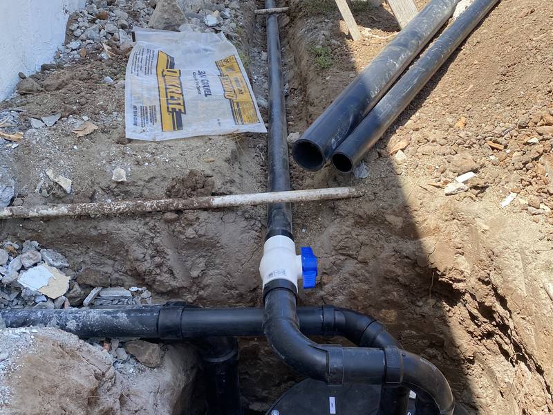 ABS drain piping and a new water line run through a trench during a repipe